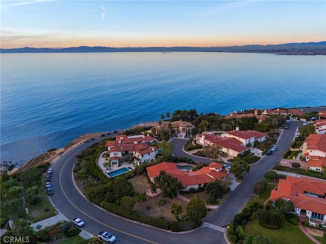 aerial view at dusk featuring a water view