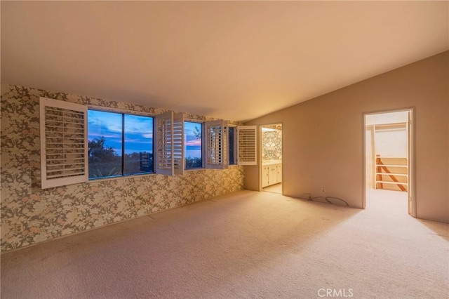 unfurnished living room with lofted ceiling and light colored carpet