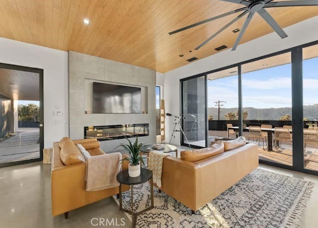 living room with ceiling fan, concrete floors, and wood ceiling