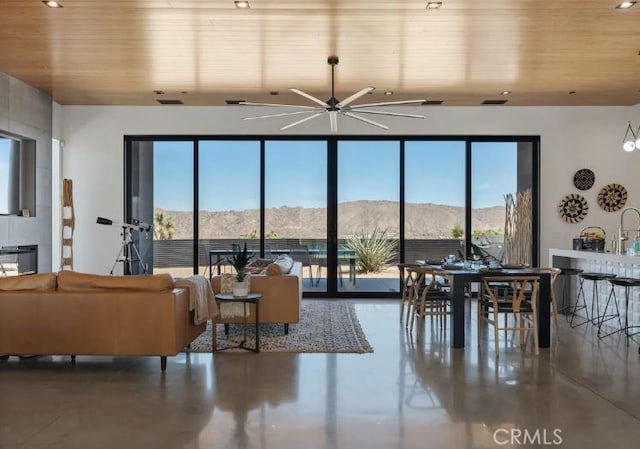 living room with wood ceiling, ceiling fan, concrete flooring, and a mountain view