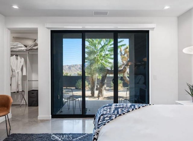 bedroom featuring a closet, access to exterior, a mountain view, and concrete floors