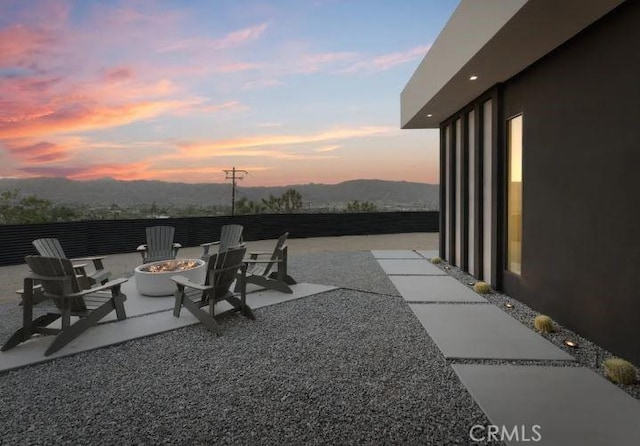 patio terrace at dusk featuring an outdoor fire pit and a mountain view