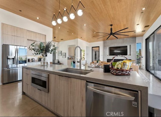 kitchen featuring appliances with stainless steel finishes, sink, a center island with sink, and wood ceiling