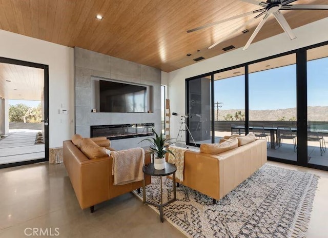 living room with a tiled fireplace, wood ceiling, and ceiling fan