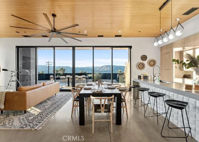 dining area with wood ceiling, a mountain view, sink, and concrete floors