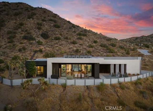 back house at dusk with a mountain view and a patio