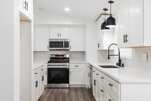 kitchen with sink, decorative light fixtures, vaulted ceiling, stainless steel appliances, and white cabinets