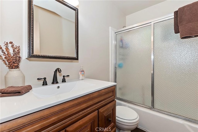 full bathroom with enclosed tub / shower combo, vanity, and toilet