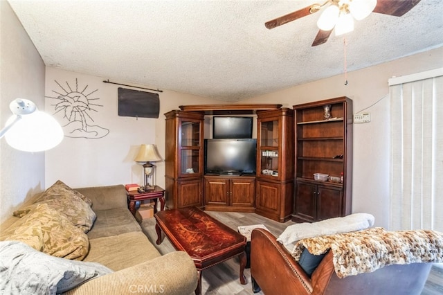 living room featuring lofted ceiling, ceiling fan, and a textured ceiling