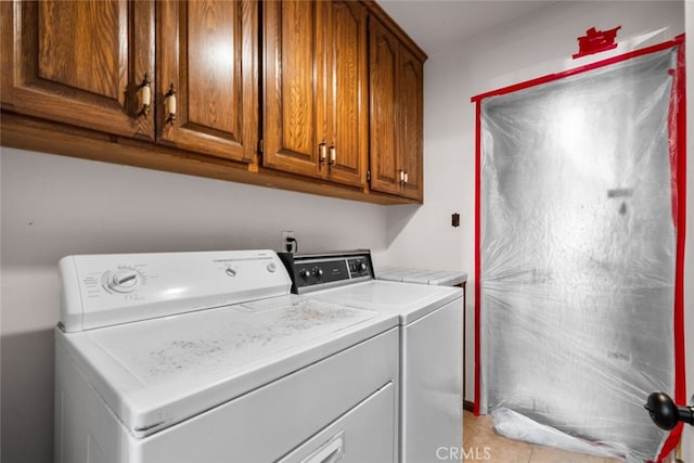 washroom featuring light tile patterned floors, washer and clothes dryer, and cabinets