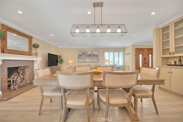 dining area with ornamental molding, light hardwood / wood-style flooring, and a tile fireplace