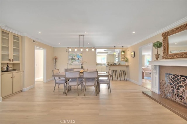 dining space with ornamental molding and light hardwood / wood-style floors