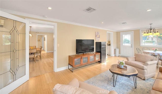 living room featuring a notable chandelier, light hardwood / wood-style flooring, and ornamental molding