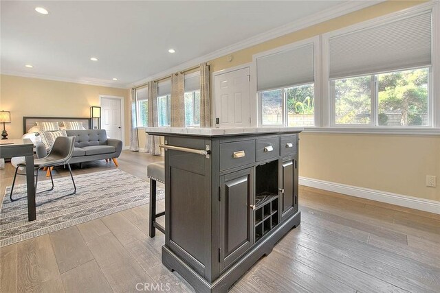 kitchen featuring crown molding, light hardwood / wood-style flooring, a center island, and plenty of natural light