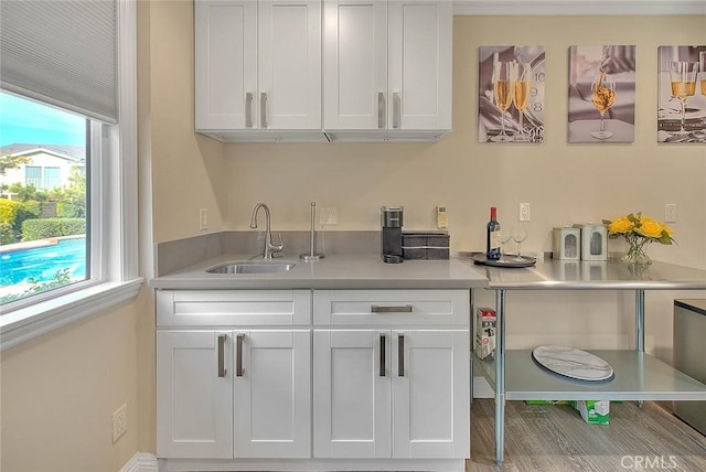 bar with white cabinetry and sink