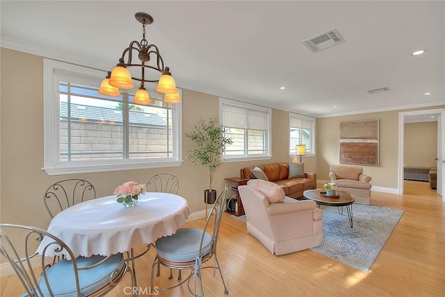 dining space with ornamental molding and light hardwood / wood-style flooring