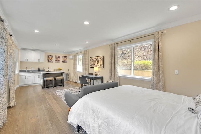 bedroom featuring ornamental molding, indoor wet bar, and light wood-type flooring