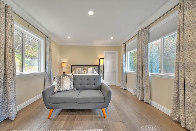 bedroom featuring ornamental molding, multiple windows, and light wood-type flooring