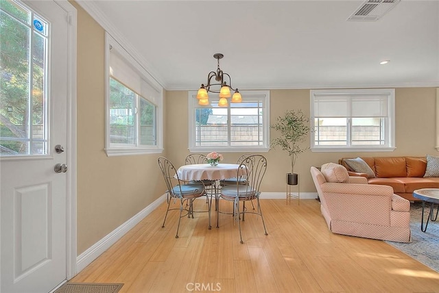 dining room with ornamental molding, light hardwood / wood-style floors, a chandelier, and a healthy amount of sunlight