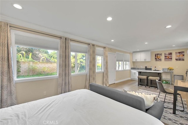 bedroom with sink, light hardwood / wood-style flooring, and ornamental molding