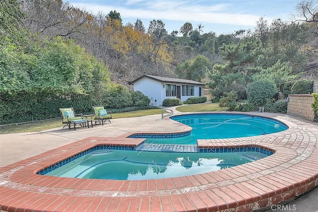 view of swimming pool with an in ground hot tub, a patio area, and an outbuilding