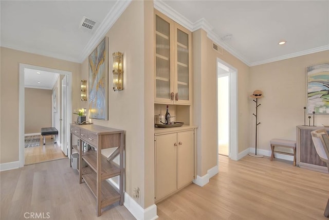 corridor with ornamental molding and light hardwood / wood-style flooring