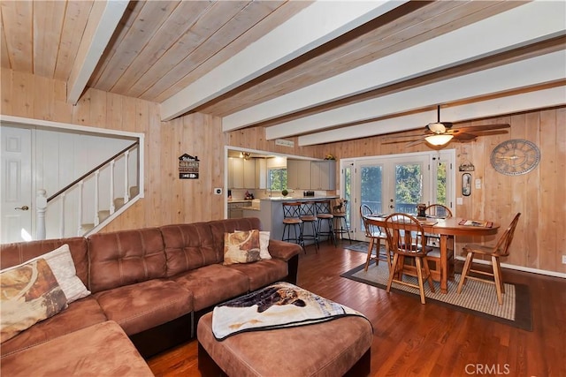 living room with wooden walls, wood finished floors, stairs, wooden ceiling, and beamed ceiling