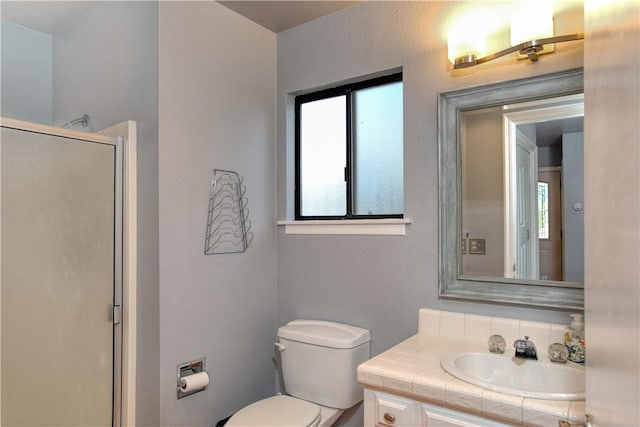 bathroom with walk in shower, vanity, and toilet