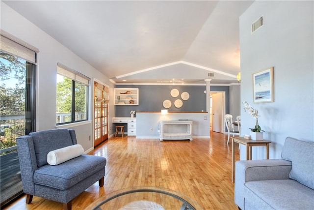 living room featuring hardwood / wood-style flooring, vaulted ceiling, and decorative columns