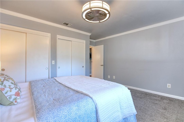 carpeted bedroom featuring crown molding and two closets