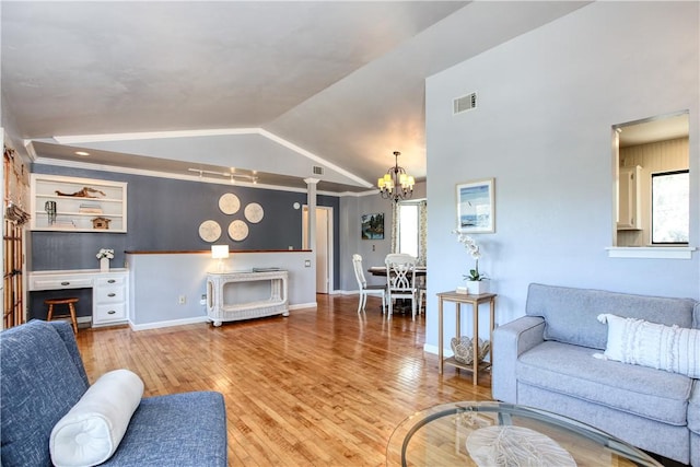 living room with lofted ceiling, hardwood / wood-style floors, a notable chandelier, and built in features