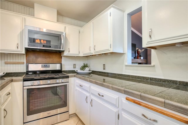 kitchen featuring tasteful backsplash, stainless steel appliances, light tile patterned floors, and white cabinets