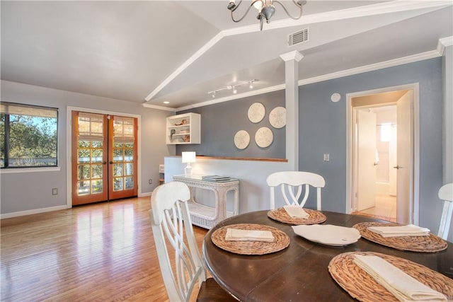 dining area with vaulted ceiling, a notable chandelier, crown molding, and light hardwood / wood-style floors