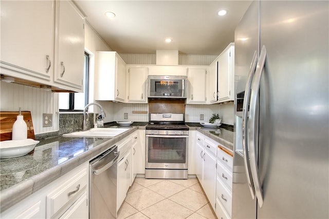 kitchen featuring appliances with stainless steel finishes, tasteful backsplash, white cabinetry, sink, and light tile patterned floors