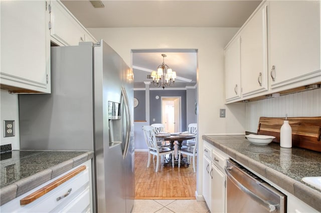 kitchen with light tile patterned floors, an inviting chandelier, stainless steel appliances, ornamental molding, and white cabinets