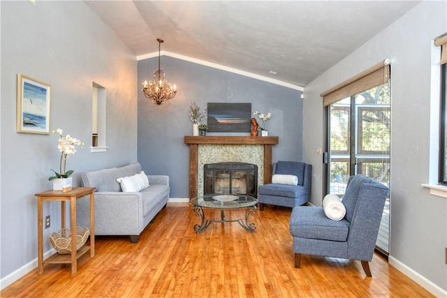 sitting room with a tiled fireplace, vaulted ceiling, an inviting chandelier, and light hardwood / wood-style flooring