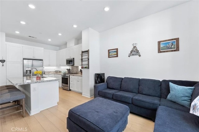 living room featuring sink and light hardwood / wood-style flooring