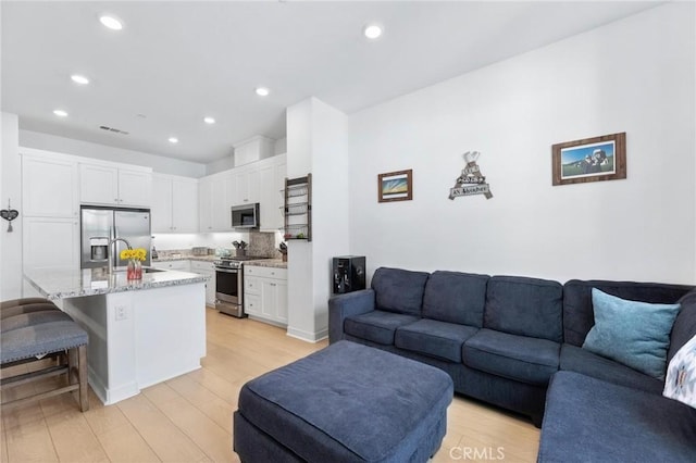 living room featuring recessed lighting, visible vents, and light wood-style flooring