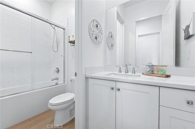 full bathroom featuring toilet, vanity, combined bath / shower with glass door, and hardwood / wood-style floors