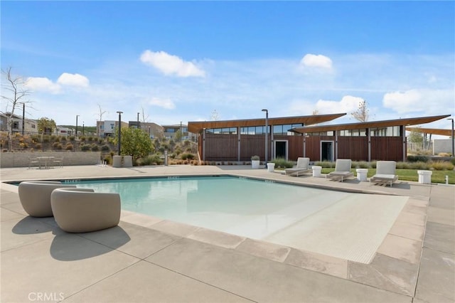 community pool with a patio area and fence