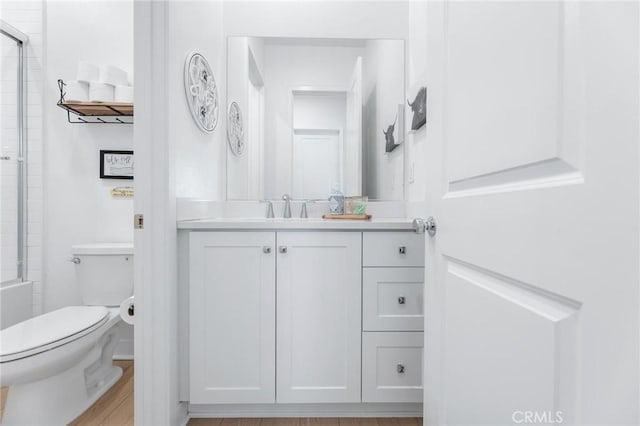 bathroom featuring hardwood / wood-style flooring, vanity, walk in shower, and toilet