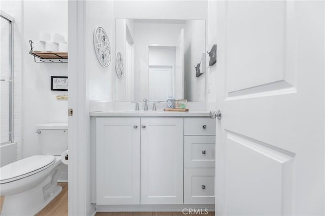 bathroom with a shower with shower door, vanity, and toilet