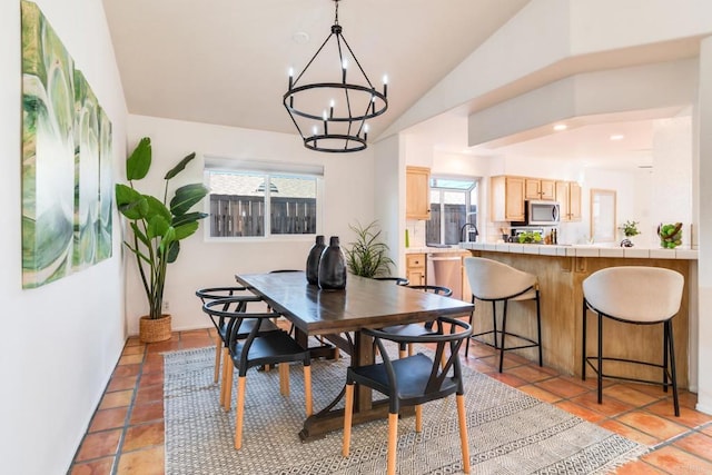 tiled dining area with an inviting chandelier, a wealth of natural light, and vaulted ceiling