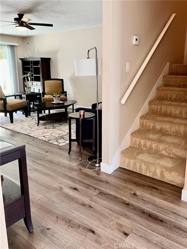 stairs featuring hardwood / wood-style floors, a textured ceiling, and ceiling fan