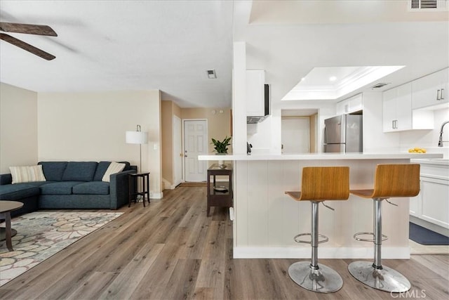 kitchen with white cabinets, stainless steel fridge, a kitchen breakfast bar, and kitchen peninsula