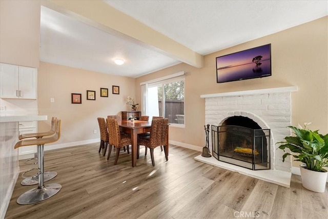 dining room featuring beamed ceiling and light hardwood / wood-style floors