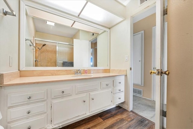 bathroom featuring vanity, tiled shower, and hardwood / wood-style floors