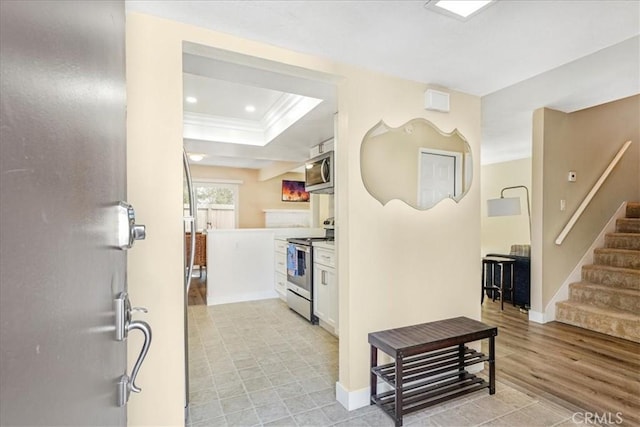 kitchen featuring a tray ceiling, crown molding, white cabinets, and appliances with stainless steel finishes