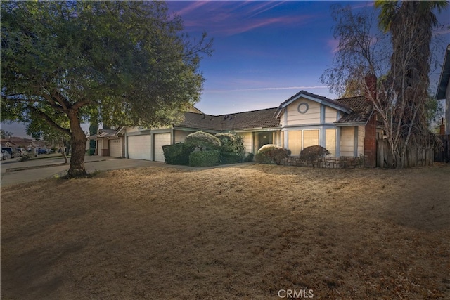 single story home featuring a garage and a yard