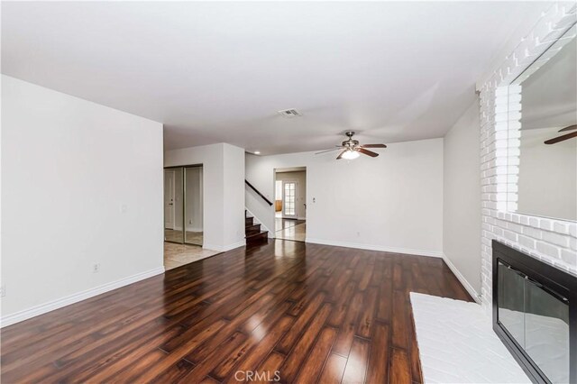 unfurnished living room with hardwood / wood-style flooring, a brick fireplace, and ceiling fan